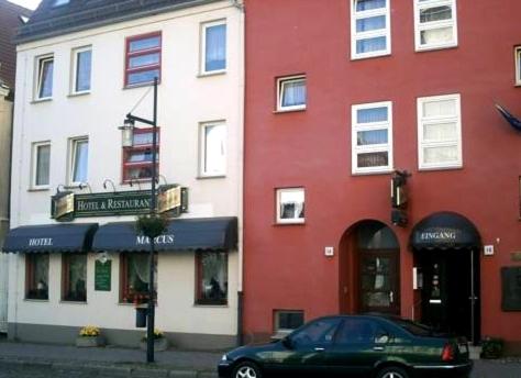 ein grünes Auto, das vor einem rot-weißen Gebäude parkt in der Unterkunft Hotel-Restaurant Marcus in Malchin