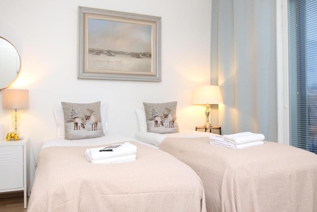 two beds in a white room with a picture on the wall at Arctic Holiday Suite in Rovaniemi