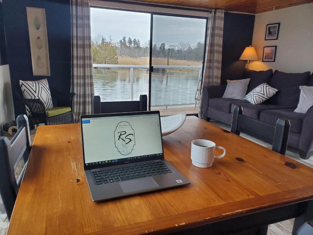 a laptop computer sitting on a wooden table in a living room at Float and Relax ON the Water Float Home in Forked River