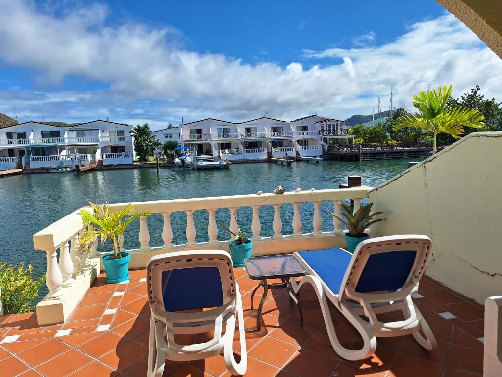 a balcony with two chairs and a table with a view of the water at Comfortable villa near the beach in Jolly Harbour