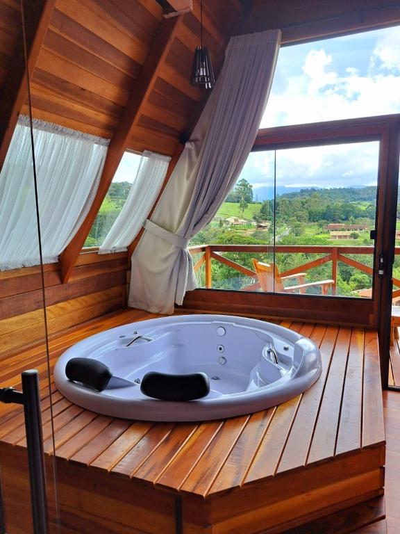 a bath tub in a room with a large window at Chalés Roma in Santo Antônio do Pinhal