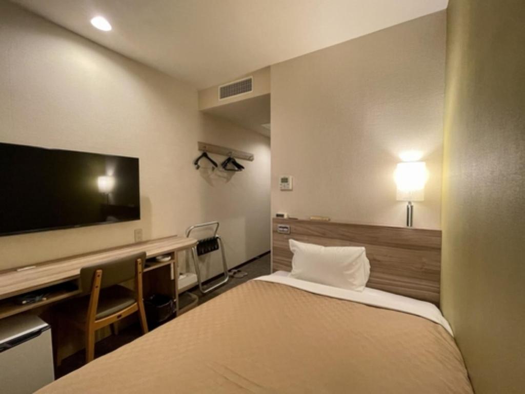 a hotel room with a bed and a flat screen tv at Kusatsu Daiichi Hotel - Vacation STAY 99256v in Kusatsu