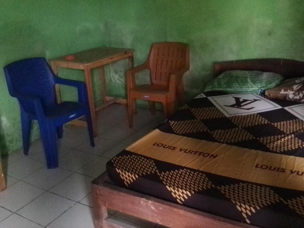 Cette chambre comprend un lit, deux chaises et une table. dans l'établissement Homestay Syariah Sederhana, à Sleman