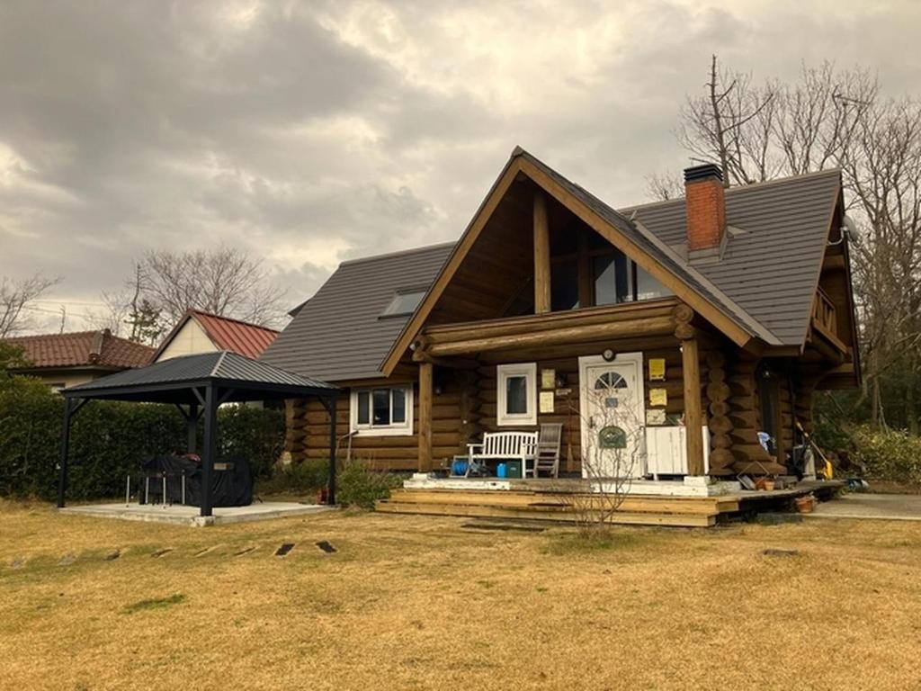 une cabane en rondins avec un porche et un parasol dans l'établissement Cottage Dejavu & Harvest - Vacation STAY 03242v, à Uwano