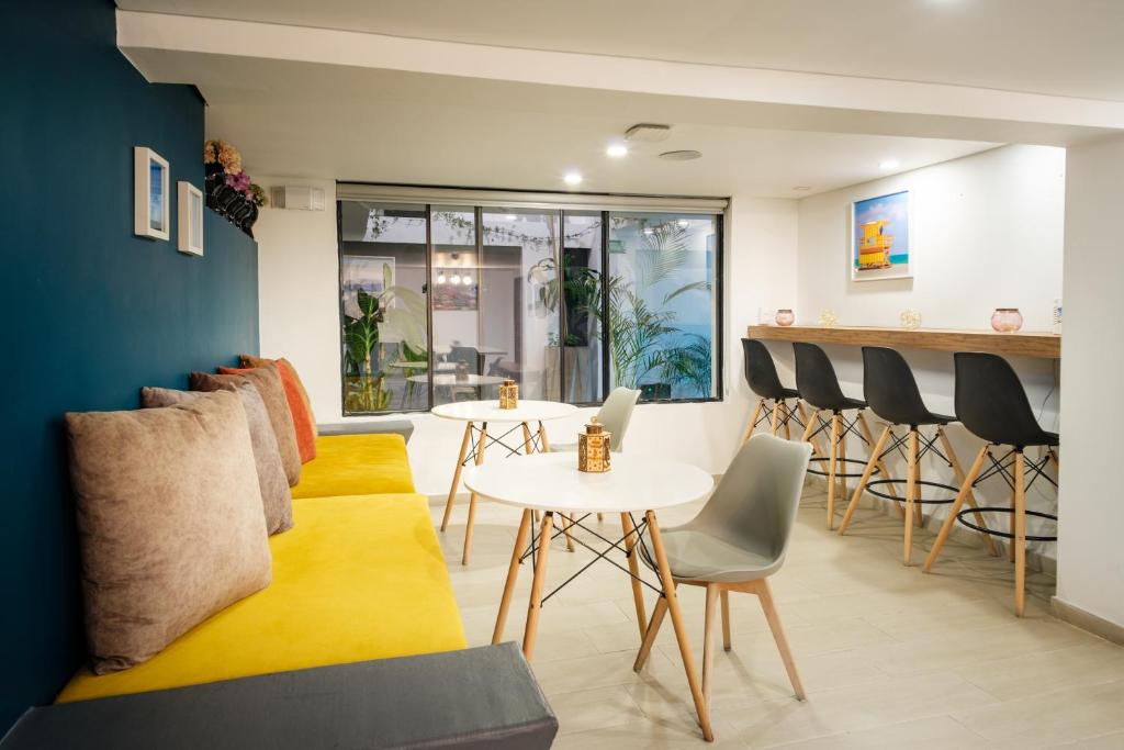 un soggiorno con divano giallo, tavoli e sedie di Palermo Home Bogota & Art Gallery a Bogotá