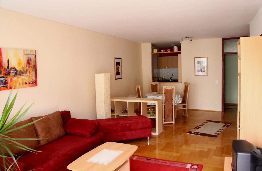 ein Wohnzimmer mit einem roten Sofa und einer Küche in der Unterkunft FeWo Bonnita - Nähe UN-Campus u. WCCB in Bonn
