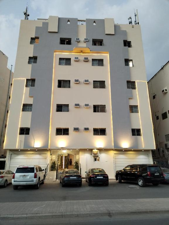 a large building with cars parked in a parking lot at Al Ghazali Suites, اجنحة الغزالي للشقق المفروشه in Medina