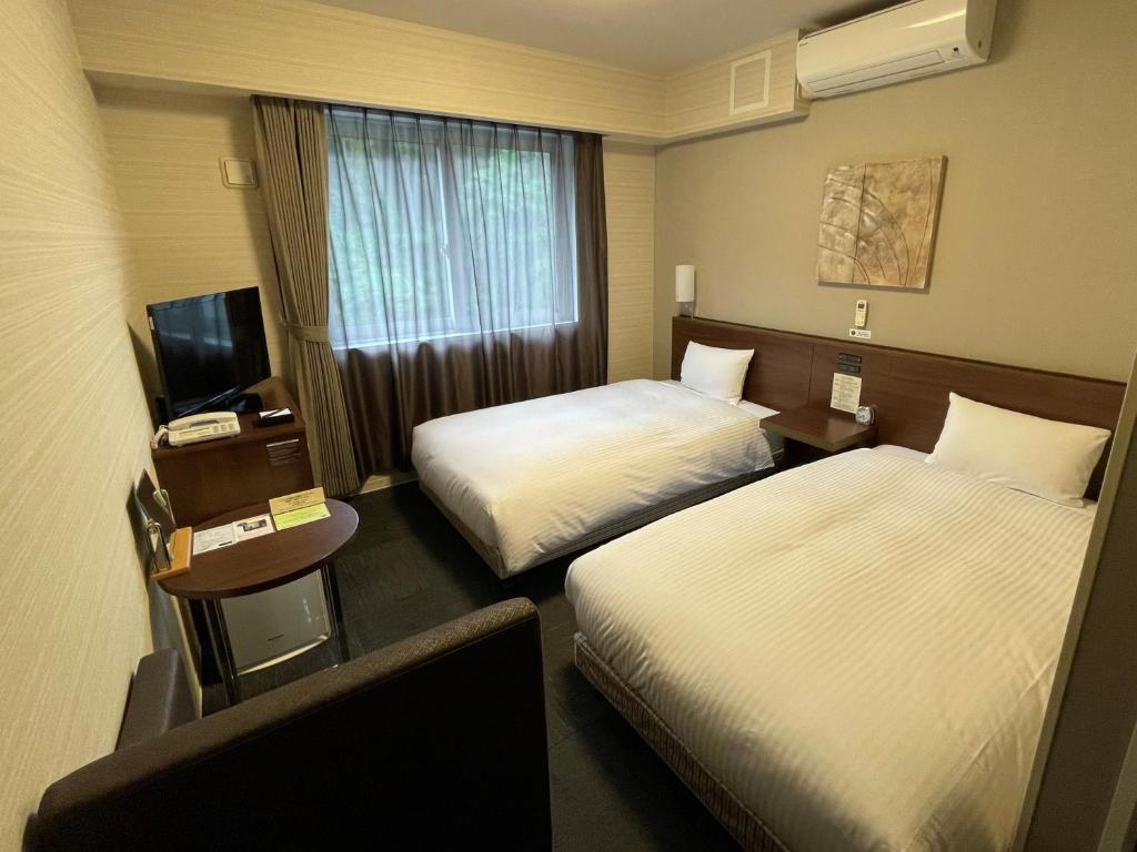 a hotel room with two beds and a television at Hotel Route-Inn Miyako in Miyako