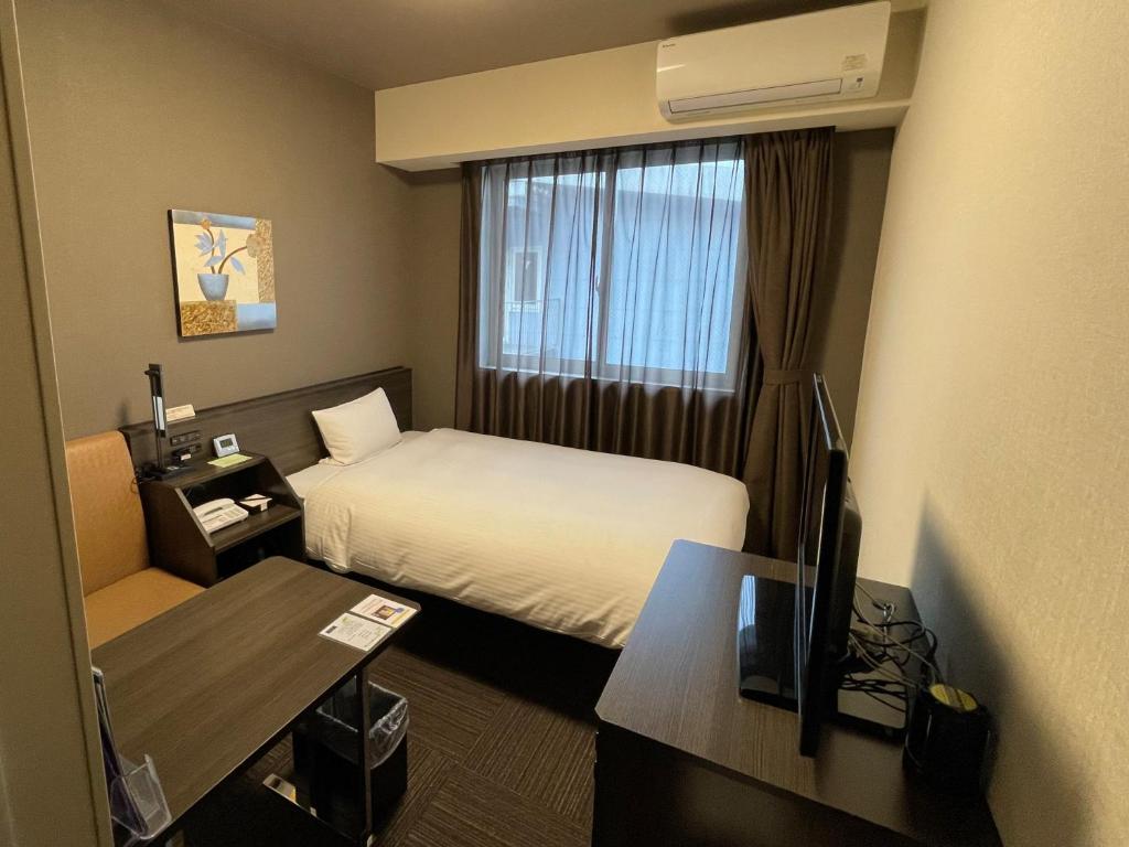 a hotel room with a bed and a desk at Hotel Route-Inn Miyako in Miyako