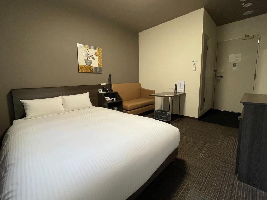 a hotel room with a bed and a chair at Hotel Route-Inn Miyako in Miyako