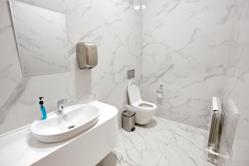 a white bathroom with a sink and a toilet at Qo'noq Tashkent Airport Hotel Sleep Lounge & Showers, Terminal 2 - TRANSIT ONLY in Tashkent