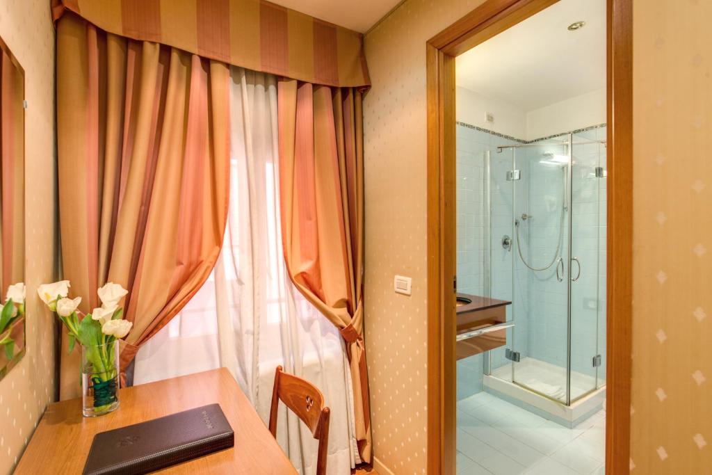 a bathroom with a table and a glass shower at Flower Garden Hotel in Rome