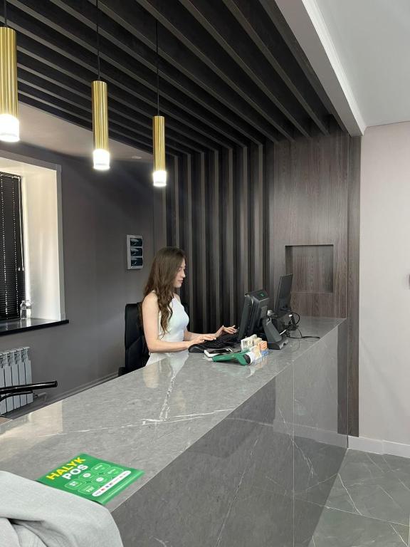 a woman sitting at a desk with a laptop at Silkway Deluxe 1 in Semey