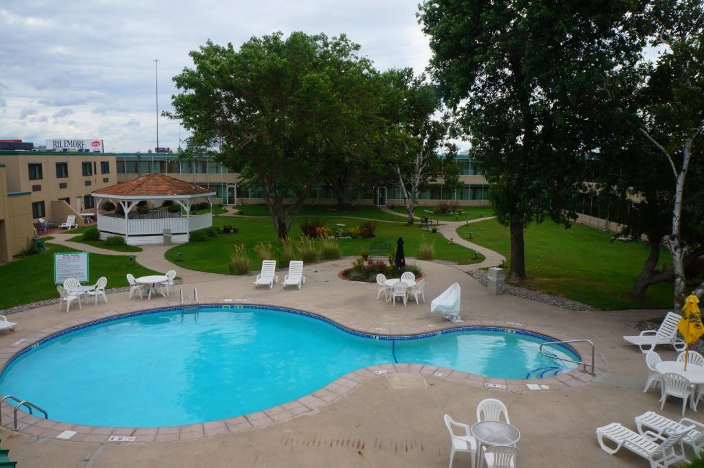 a swimming pool with chairs and a gazebo at The Biltmore Hotel & Suites Main Avenue in Fargo