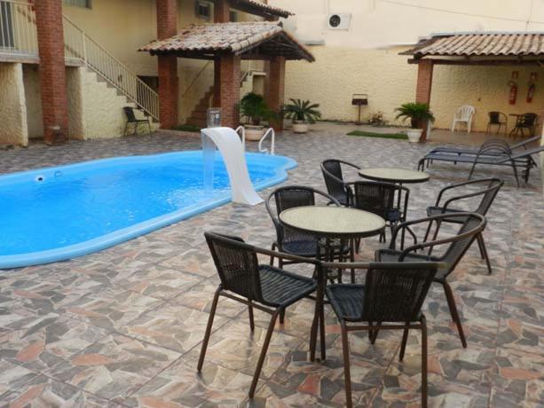 a patio with tables and chairs next to a swimming pool at Hotel Estrela Palmas in Palmas