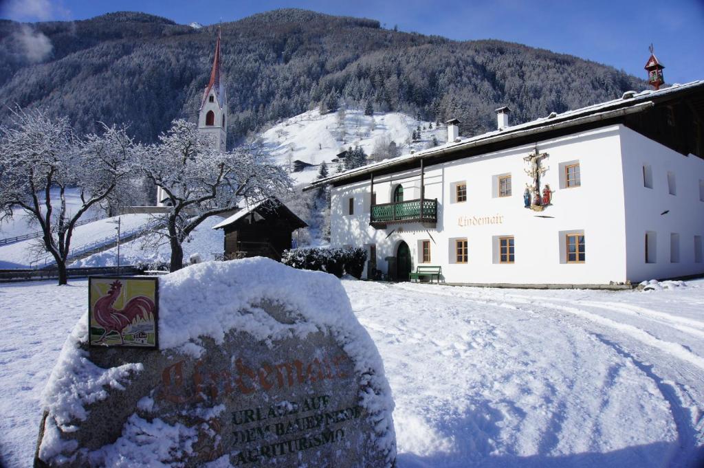 a building with a sign in the snow with a church at Lindemair in Lutago
