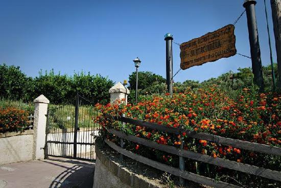 a garden with flowers and a sign on a fence at Eco-bio Agriturismo Santacinnara in Soveria Simeri