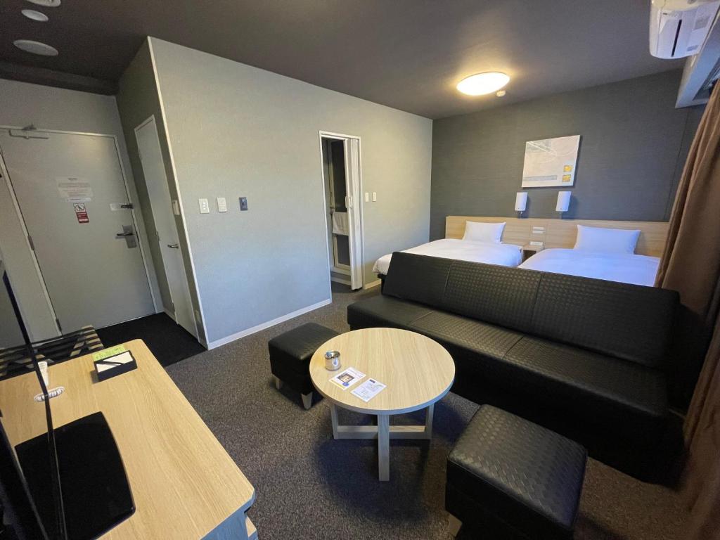 a hotel room with a couch and a bed and a table at Hotel Route-Inn Miyako in Miyako
