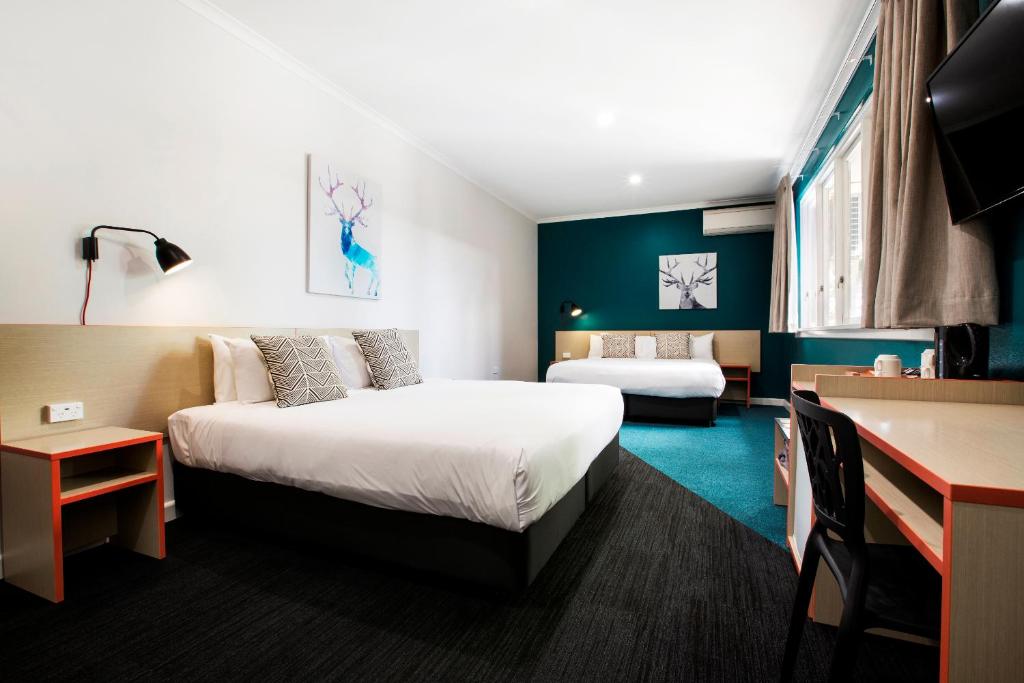 a hotel room with two beds and a desk at Greenacre Hotel in Sydney