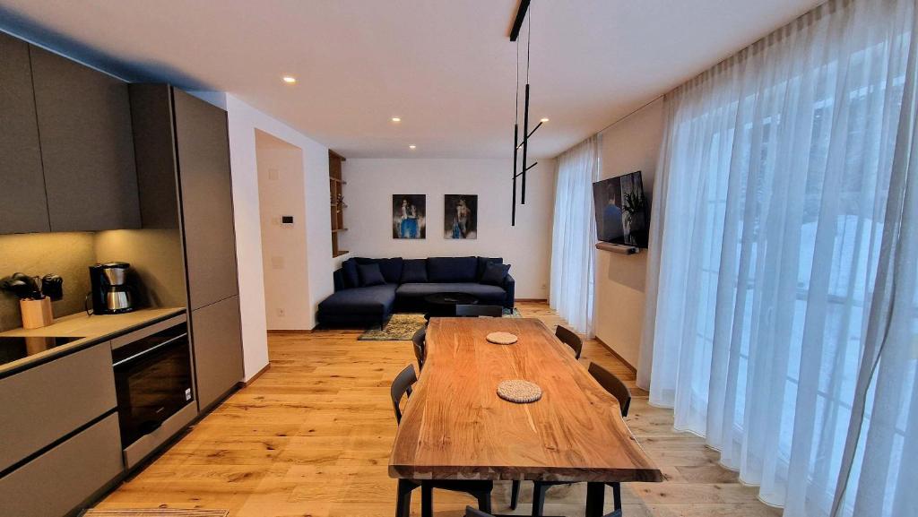 a living room with a wooden table and a kitchen at Silberdistel Brand-new luxury apartment with private terrace in Saas-Fee