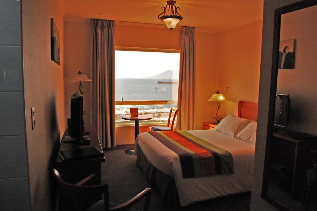 アントファガスタにあるHotel Florencia Suites & Apartmentsのベッド付きのホテルルームで、海の景色を望めます。