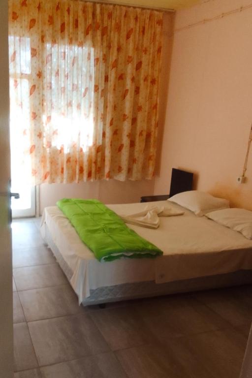 a bedroom with a bed with a green blanket on it at Бунгала Дъбрава in Shkorpilovtsi
