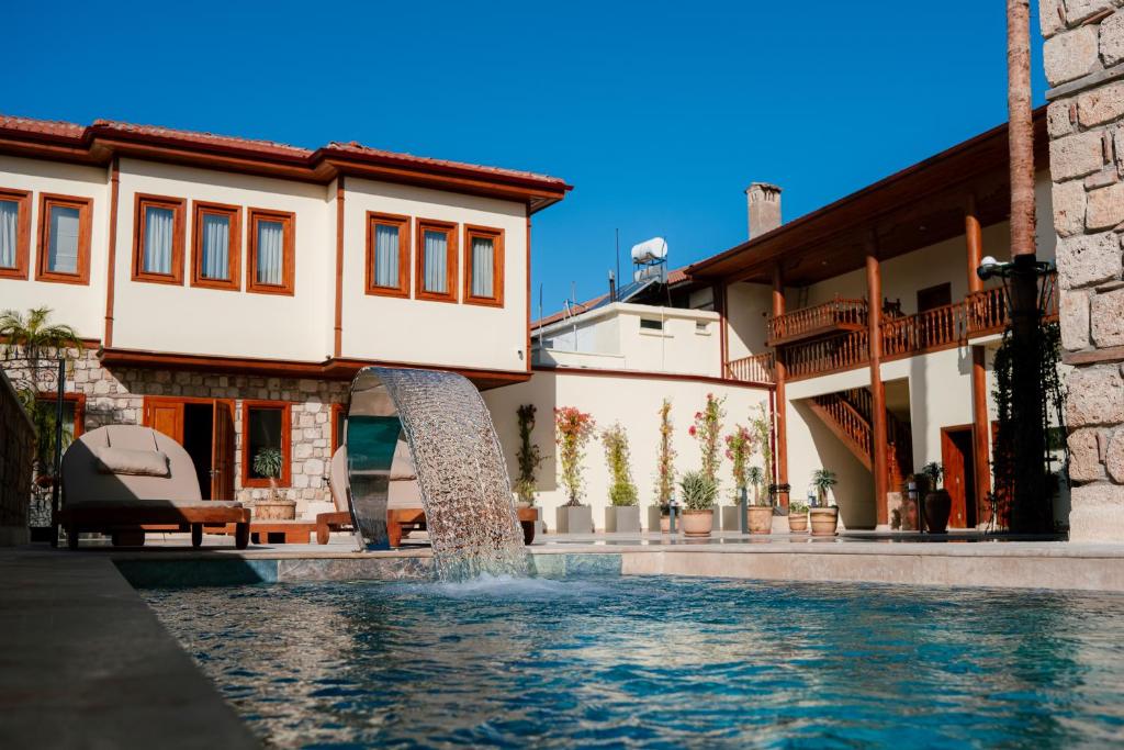 a swimming pool with a fountain in front of a house at Dumos Suite Hotel in Antalya