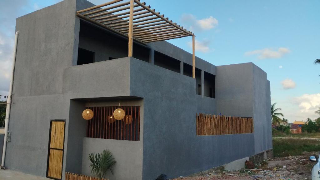 ein graues Gebäude mit einer Holztür und einem Zaun in der Unterkunft Vila Malie milagres in São Miguel dos Milagres