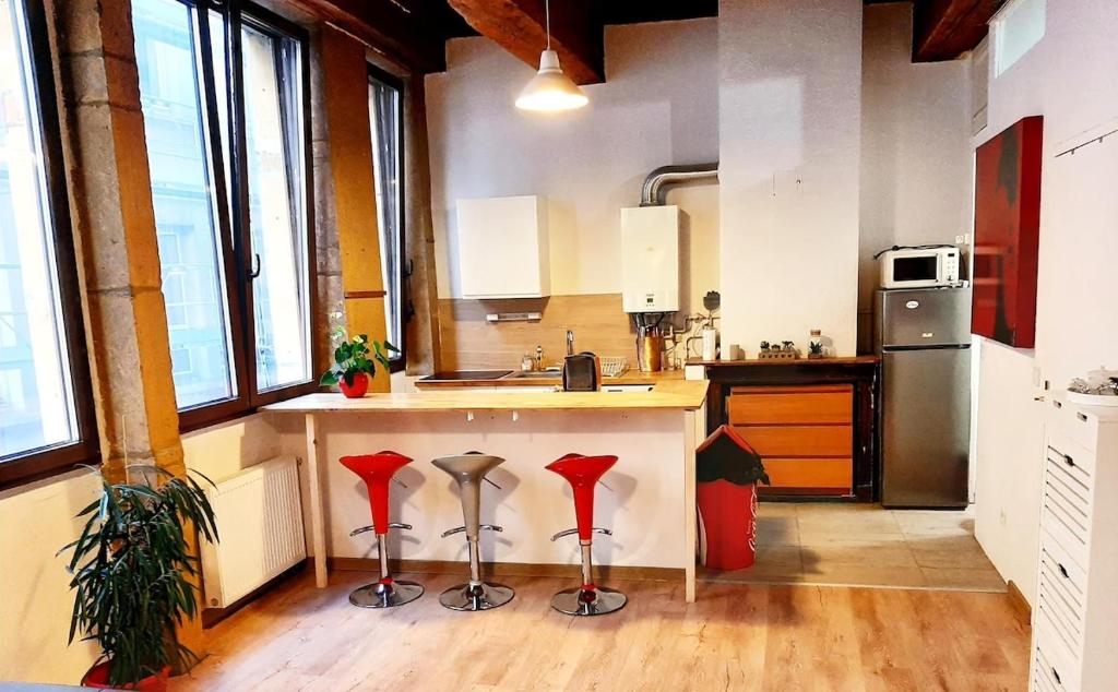 une cuisine avec comptoir et tabourets rouges dans l'établissement Lyon Centre Warm apartment full of charm, à Lyon