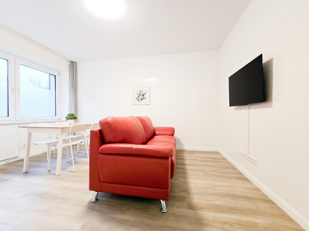 a red chair in a living room with a table at Tolstov Apartments - 2 Room Apartment - 25 min Messe DUS in Duisburg