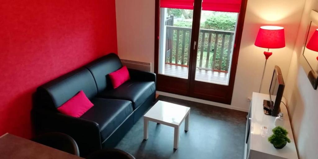 - un salon avec un canapé noir et des oreillers roses dans l'établissement Confortable 2 pièces calme à 200 m plage wifi, à Cabourg
