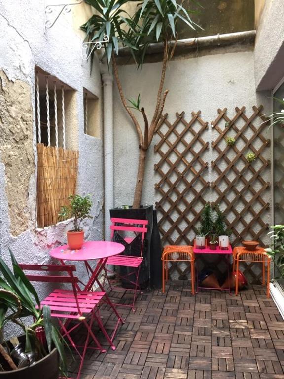 une terrasse avec des tables et des chaises roses et une clôture dans l'établissement Apartment, wifi, city center, terrasse, à Montpellier