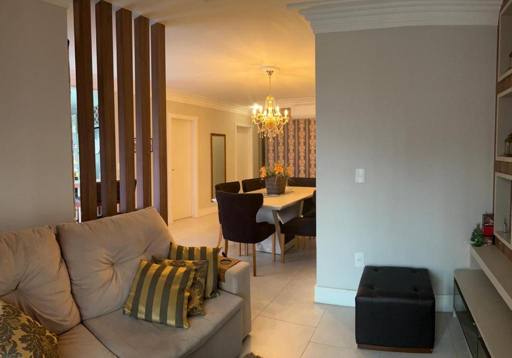 a living room with a couch and a dining room at Apto 3 Suítes e Garagem Dupla Itapema Meia Praia em Ótima Localização in Itapema