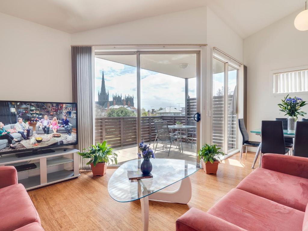 a living room with a tv and a large window at McKillop Geelong by Gold Star Stays in Geelong