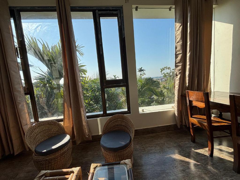 een kamer met een tafel, stoelen en ramen bij Choudhury's Stay in Helāpākari