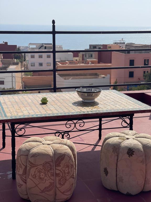 Tamraght OuzdarにあるJamal's Holiday apartementsのバルコニーにテーブルとスツール2脚
