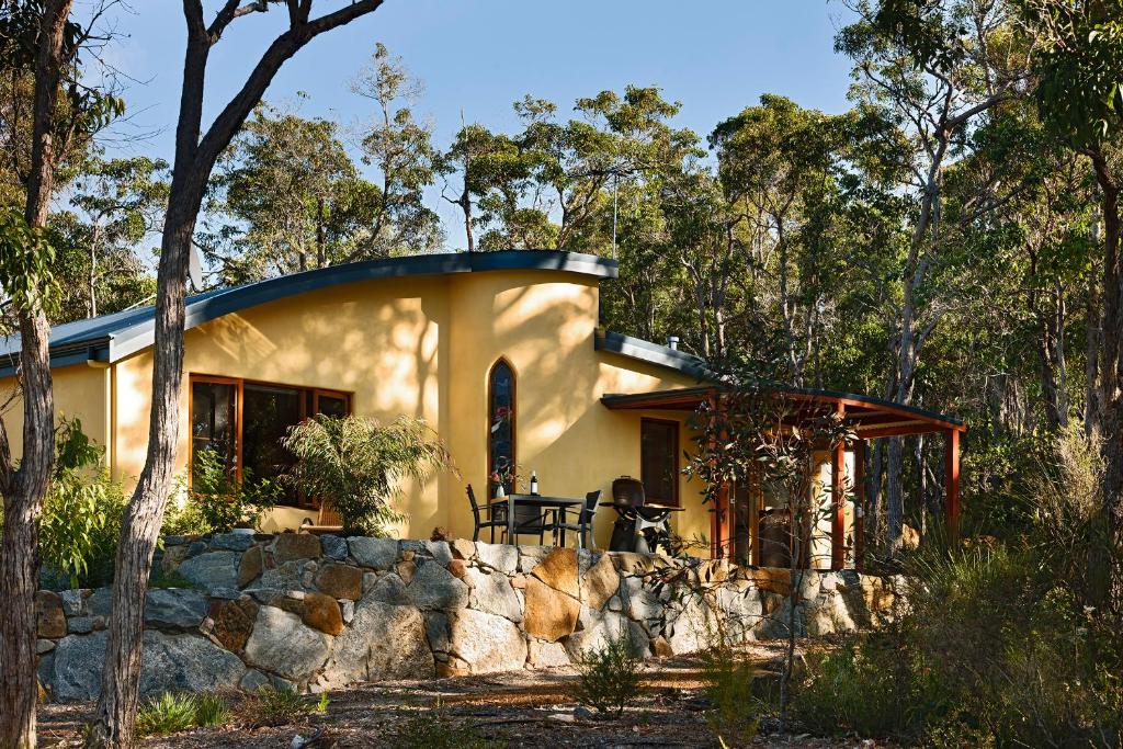 een huis in het bos met een stenen muur bij Aiyana Retreat in Denmark