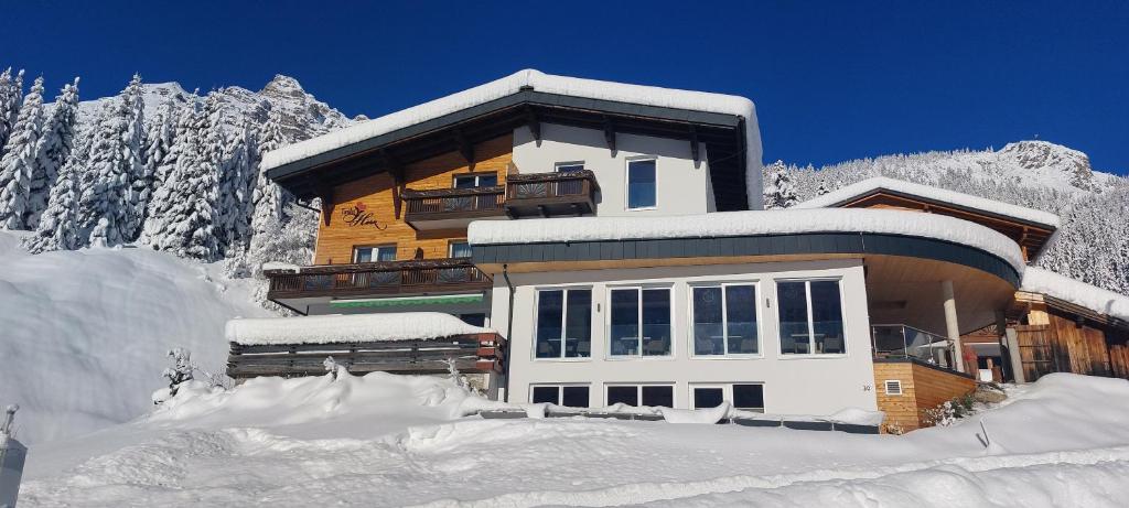 una casa nella neve di fronte a una montagna di Hotel Tiroler Herz a Hinterhornbach