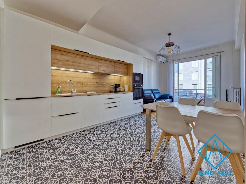 une cuisine avec des armoires blanches et une table et des chaises dans l'établissement Golden Square, à Nice
