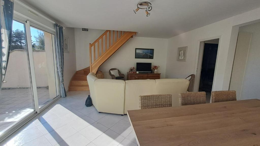 un salon avec un canapé et un escalier dans l'établissement Au bord de la mer, à Saint-Jean-de-la-Rivière