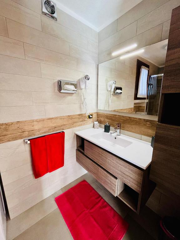W łazience znajduje się biała umywalka i czerwone ręczniki. w obiekcie Home, sweet home w Livigno