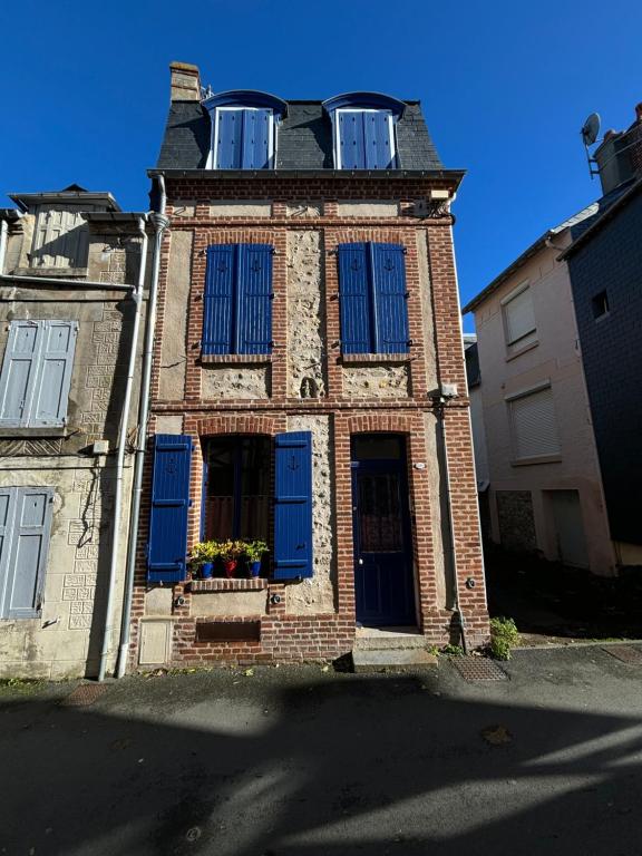 un vieux bâtiment en briques avec des volets bleus dans l'établissement La maison bleue, à Villerville