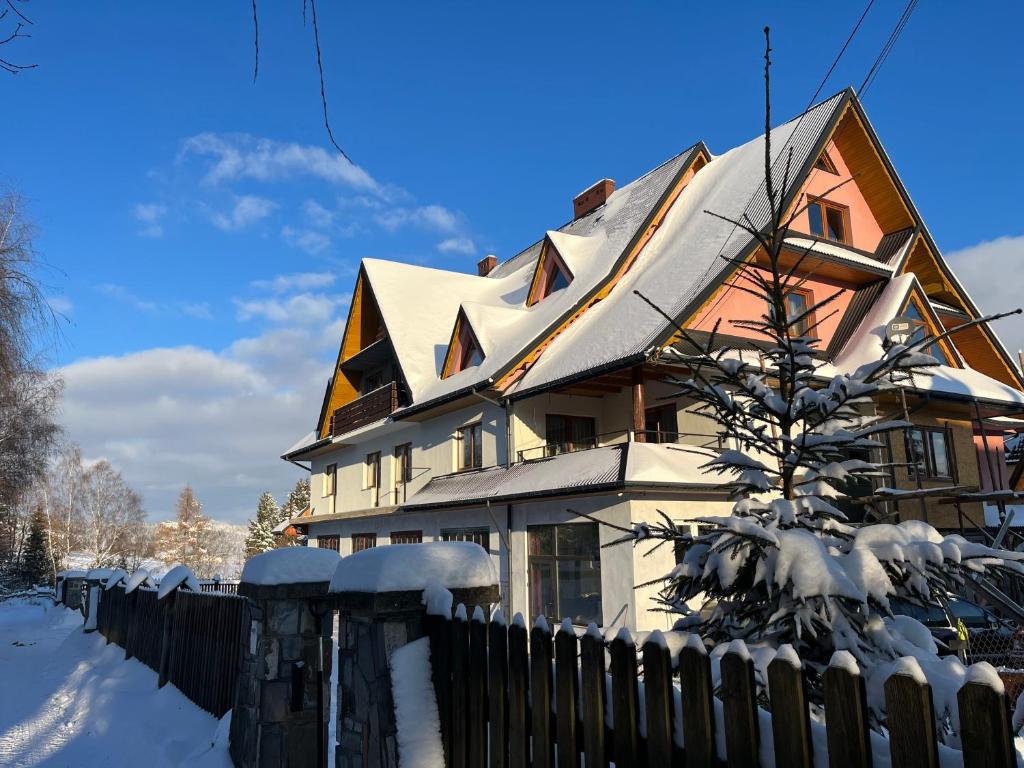 una casa cubierta de nieve con una valla en Gościniec na Wierchu, en Bukowina Tatrzańska