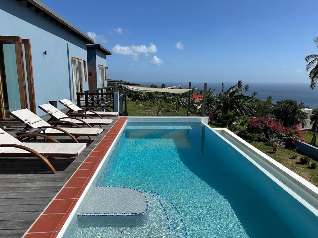 Una piscina con tumbonas al lado de una casa. en Paradise Factory St Lucia, en Choiseul