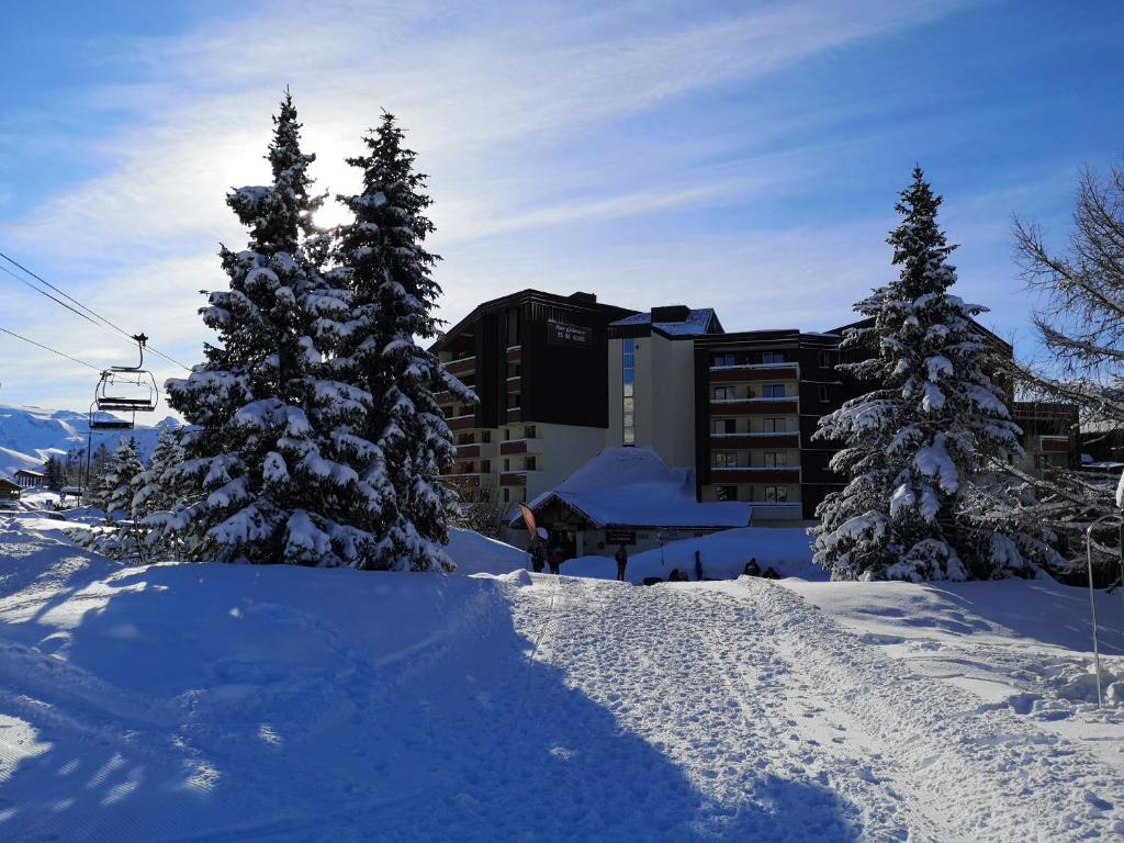 un groupe d'arbres dans la neige avec une remontée mécanique dans l'établissement Grand T2 résidence avec piscine sauna, à Huez