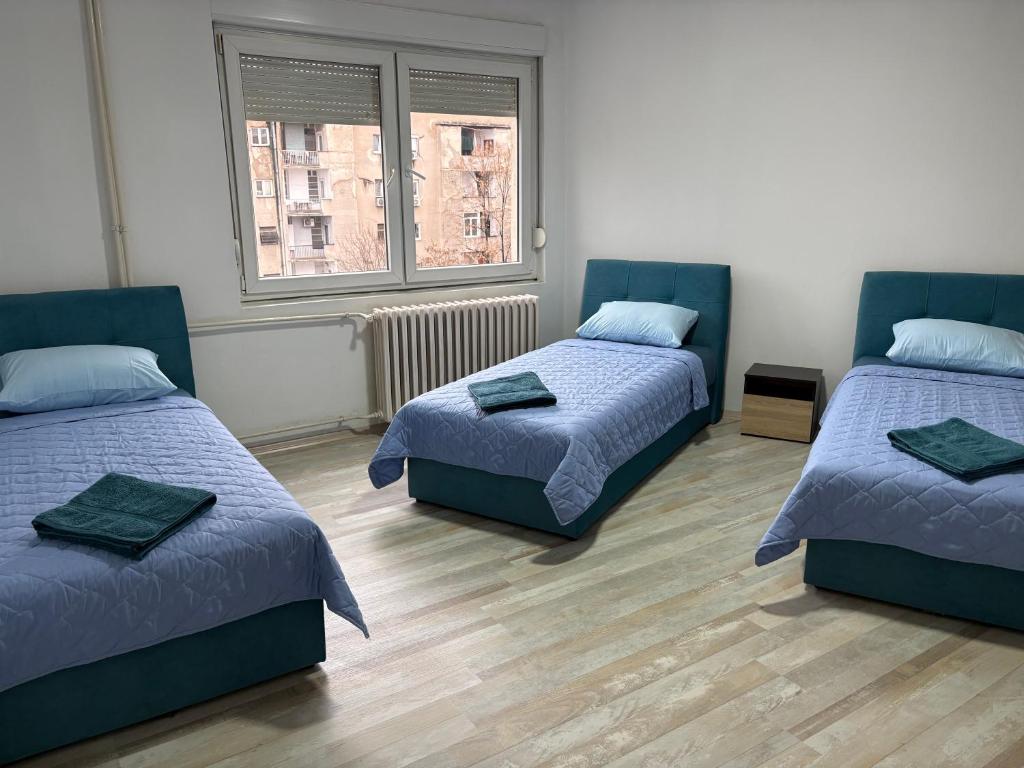 a room with two beds and two windows at Dubai Marina Guest House in Skopje