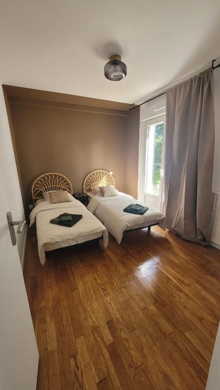 une chambre avec deux lits et une fenêtre dans l'établissement Parenthèse en Terre Breizh, à Bohal