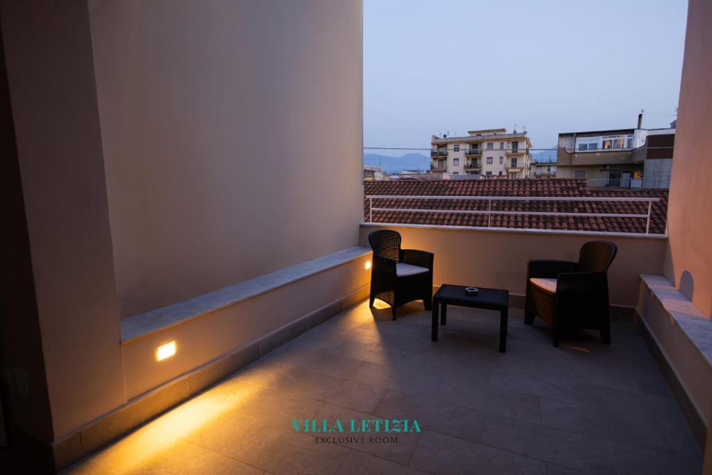 Un balcón con dos sillas y una mesa. en Villa Letizia - Sky blu pompei room, en Boscoreale