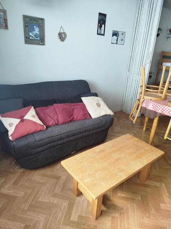un salon avec un canapé noir et une table en bois dans l'établissement Résidence Le Tourmalet - maeva Home - Studio 4 personnes - Confort MAE-7961, à La Mongie