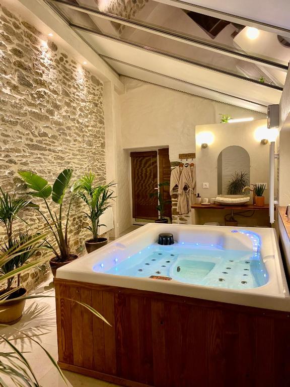 - une grande baignoire dans une pièce ornée de plantes dans l'établissement Le Pré de la Mer Suite & SPA Privatif, à Querqueville